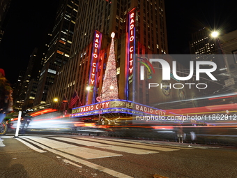 Car and foot traffic goes by Radio City Music Hall in New York, N.Y., on December 12, 2024. The photo is taken as a long exposure. (