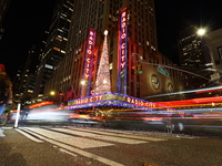 Car and foot traffic goes by Radio City Music Hall in New York, N.Y., on December 12, 2024. The photo is taken as a long exposure. (