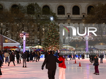 People skate in the Winter Village in Bryant Park in New York, N.Y., on December 12, 2024. The photo is taken as a long exposure. (