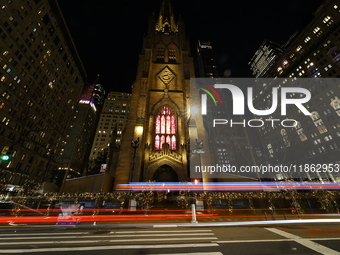 Traffic and pedestrians make their way along Broadway past Trinity Church in New York, N.Y., on December 12, 2024. (