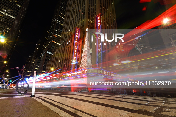 Car and foot traffic goes by Radio City Music Hall in New York, N.Y., on December 12, 2024. The photo is taken as a long exposure. 