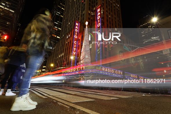 Car and foot traffic goes by Radio City Music Hall in New York, N.Y., on December 12, 2024. The photo is taken as a long exposure. 