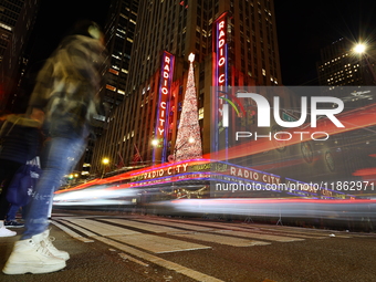 Car and foot traffic goes by Radio City Music Hall in New York, N.Y., on December 12, 2024. The photo is taken as a long exposure. (