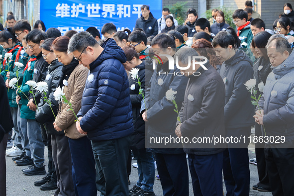 People stand in silence in front of the memorial for the victims of the Nanjing Massacre by Japanese invaders at the Zhengjue Temple in Nanj...