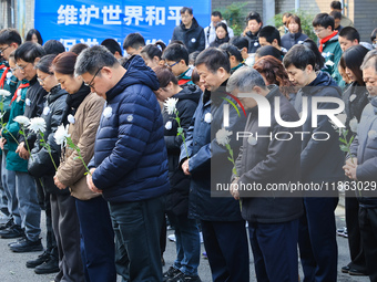 People stand in silence in front of the memorial for the victims of the Nanjing Massacre by Japanese invaders at the Zhengjue Temple in Nanj...