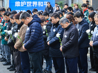 People stand in silence in front of the memorial for the victims of the Nanjing Massacre by Japanese invaders at the Zhengjue Temple in Nanj...