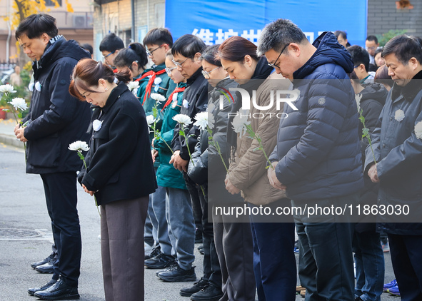 People stand in silence in front of the memorial for the victims of the Nanjing Massacre by Japanese invaders at the Zhengjue Temple in Nanj...