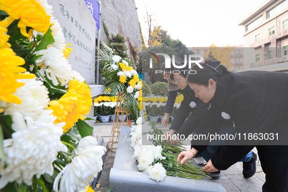 People present flowers to the memorial for the victims of the Nanjing Massacre by Japanese invaders at Zhengjue Temple in Nanjing, East Chin...