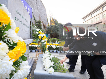 People present flowers to the memorial for the victims of the Nanjing Massacre by Japanese invaders at Zhengjue Temple in Nanjing, East Chin...