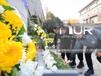 People present flowers to the memorial for the victims of the Nanjing Massacre by Japanese invaders at Zhengjue Temple in Nanjing, East Chin...