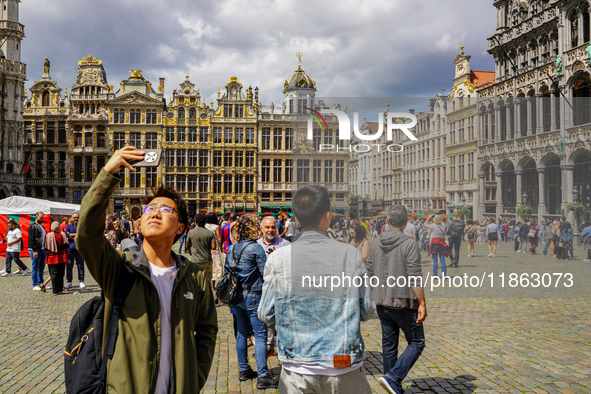 An Asian tourist takes a selfie with his smartphone, capturing the historic charm of the Grand Place in Brussels, Belgium, on July 30, 2023....