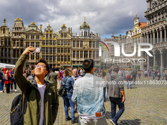 An Asian tourist takes a selfie with his smartphone, capturing the historic charm of the Grand Place in Brussels, Belgium, on July 30, 2023....