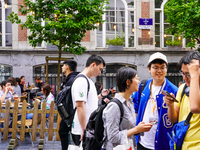 A group of Asian tourists gathers to check their smartphones, searching for directions while exploring the streets in Brussels, Belgium, on...