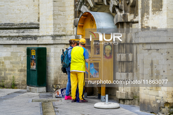 Two people engage with a public bookcase filled with lending books in Brussels, Belgium, on July 30, 2023. This free book exchange initiativ...