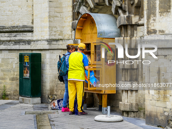 Two people engage with a public bookcase filled with lending books in Brussels, Belgium, on July 30, 2023. This free book exchange initiativ...