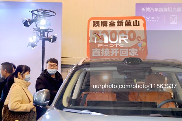 Exhibitors present subsidies and preferential promotion measures at the 16th Shandong International Auto Show 2024 in Qingdao, China, on Dec...