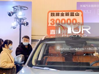 Exhibitors present subsidies and preferential promotion measures at the 16th Shandong International Auto Show 2024 in Qingdao, China, on Dec...