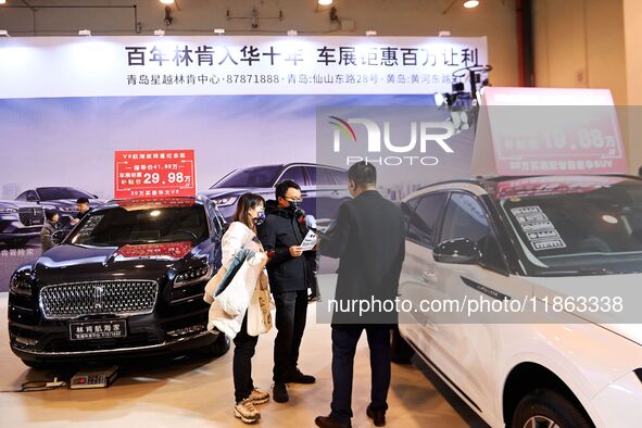 Exhibitors present subsidies and preferential promotion measures at the 16th Shandong International Auto Show 2024 in Qingdao, China, on Dec...