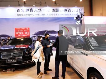 Exhibitors present subsidies and preferential promotion measures at the 16th Shandong International Auto Show 2024 in Qingdao, China, on Dec...