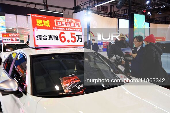 Exhibitors present subsidies and preferential promotion measures at the 16th Shandong International Auto Show 2024 in Qingdao, China, on Dec...