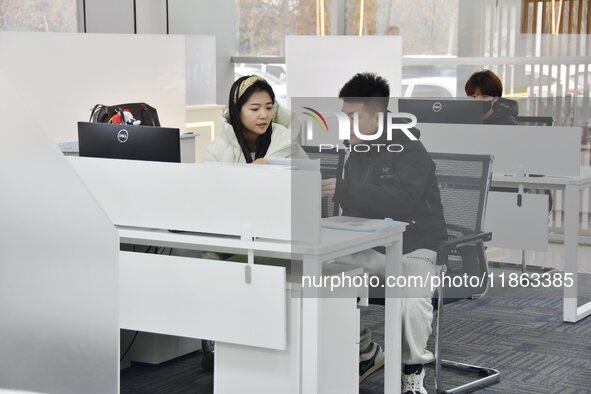 A staff member (1st L) guides residents to handle medical insurance at the Yongnian District government affairs service center in Handan, Ch...