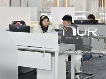 A staff member (1st L) guides residents to handle medical insurance at the Yongnian District government affairs service center in Handan, Ch...