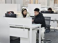 A staff member (1st L) guides residents to handle medical insurance at the Yongnian District government affairs service center in Handan, Ch...