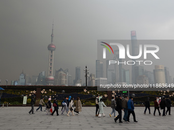 Chinese and foreign tourists view the Lujiazui high-rise buildings across the Huangpu River near the Bund landscape platform in Shanghai, Ch...