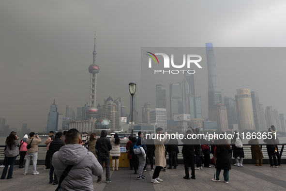 Chinese and foreign tourists view the Lujiazui high-rise buildings across the Huangpu River near the Bund landscape platform in Shanghai, Ch...