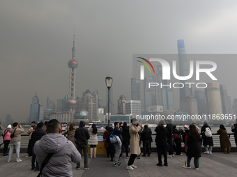 Chinese and foreign tourists view the Lujiazui high-rise buildings across the Huangpu River near the Bund landscape platform in Shanghai, Ch...