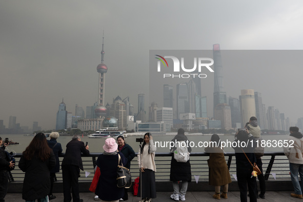 Chinese and foreign tourists view the Lujiazui high-rise buildings across the Huangpu River near the Bund landscape platform in Shanghai, Ch...