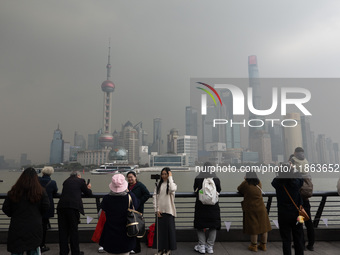 Chinese and foreign tourists view the Lujiazui high-rise buildings across the Huangpu River near the Bund landscape platform in Shanghai, Ch...