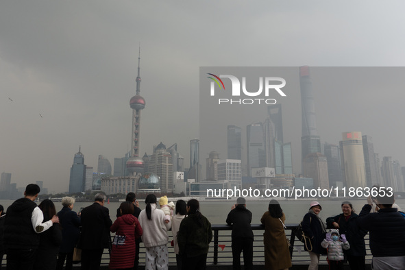 Chinese and foreign tourists view the Lujiazui high-rise buildings across the Huangpu River near the Bund landscape platform in Shanghai, Ch...