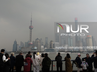 Chinese and foreign tourists view the Lujiazui high-rise buildings across the Huangpu River near the Bund landscape platform in Shanghai, Ch...