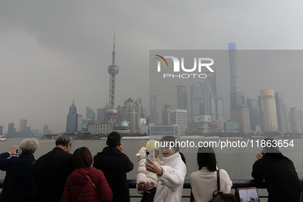 Chinese and foreign tourists view the Lujiazui high-rise buildings across the Huangpu River near the Bund landscape platform in Shanghai, Ch...