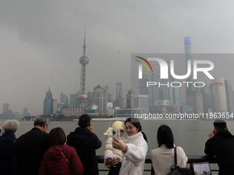 Chinese and foreign tourists view the Lujiazui high-rise buildings across the Huangpu River near the Bund landscape platform in Shanghai, Ch...