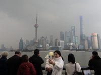 Chinese and foreign tourists view the Lujiazui high-rise buildings across the Huangpu River near the Bund landscape platform in Shanghai, Ch...