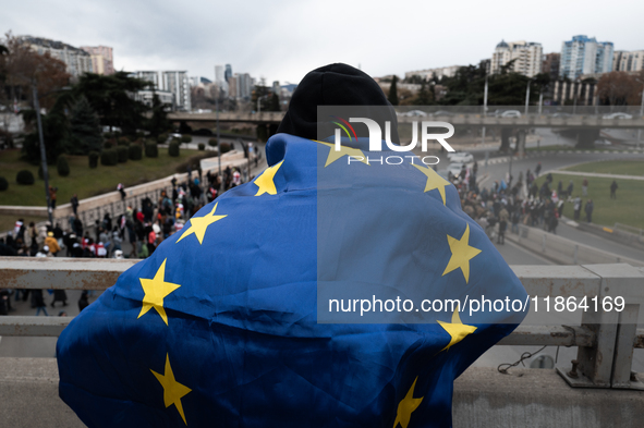 A man wears a European flag as private sector workers, students, and protesters take to the streets for a demonstration against the Georgian...