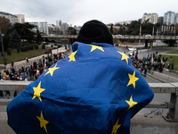 A man wears a European flag as private sector workers, students, and protesters take to the streets for a demonstration against the Georgian...