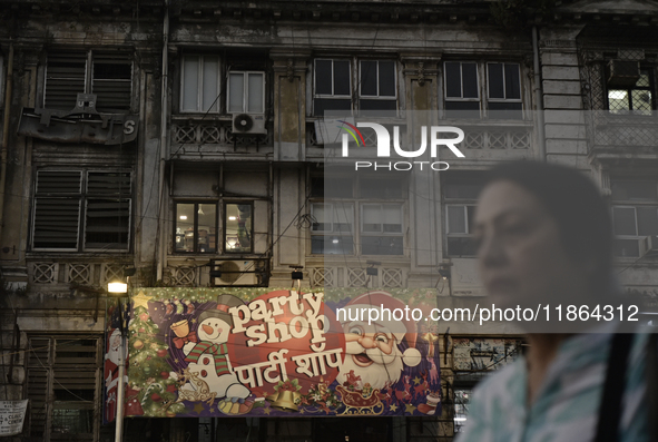 A woman walks past a billboard of a shop selling Christmas items and party items at a market ahead of the Christmas celebrations in Mumbai,...