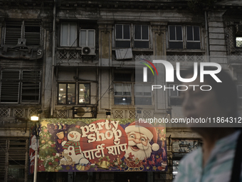 A woman walks past a billboard of a shop selling Christmas items and party items at a market ahead of the Christmas celebrations in Mumbai,...