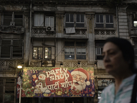 A woman walks past a billboard of a shop selling Christmas items and party items at a market ahead of the Christmas celebrations in Mumbai,...