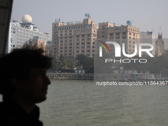 A man travels on a ferry in the waters of the Ganges River while the State Bank of India (SBI) regional office building is pictured in Kolka...