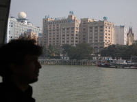 A man travels on a ferry in the waters of the Ganges River while the State Bank of India (SBI) regional office building is pictured in Kolka...