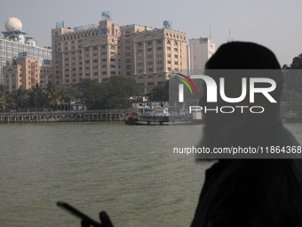 A man travels on a ferry in the waters of the Ganges River while the State Bank of India (SBI) regional office building is pictured in Kolka...