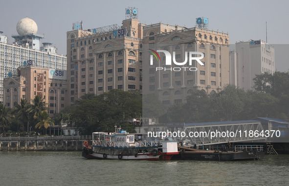 Passengers wait for a ferry on a jetty into the Ganges River while the State Bank of India (SBI) regional office building is pictured in Kol...