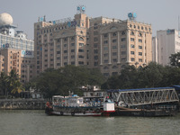 Passengers wait for a ferry on a jetty into the Ganges River while the State Bank of India (SBI) regional office building is pictured in Kol...