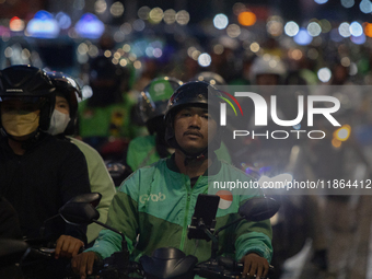 A motorcycle taxi rider is caught in traffic congestion on a street in Jakarta, Indonesia, on December 13, 2024. (