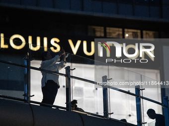 People take a photograph near a shopping center in Jakarta, Indonesia, on December 13, 2024. (