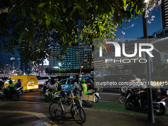 People walk in the business district of Jakarta, Indonesia, on December 12, 2024, during clear weather as evening approaches. The Regional D...